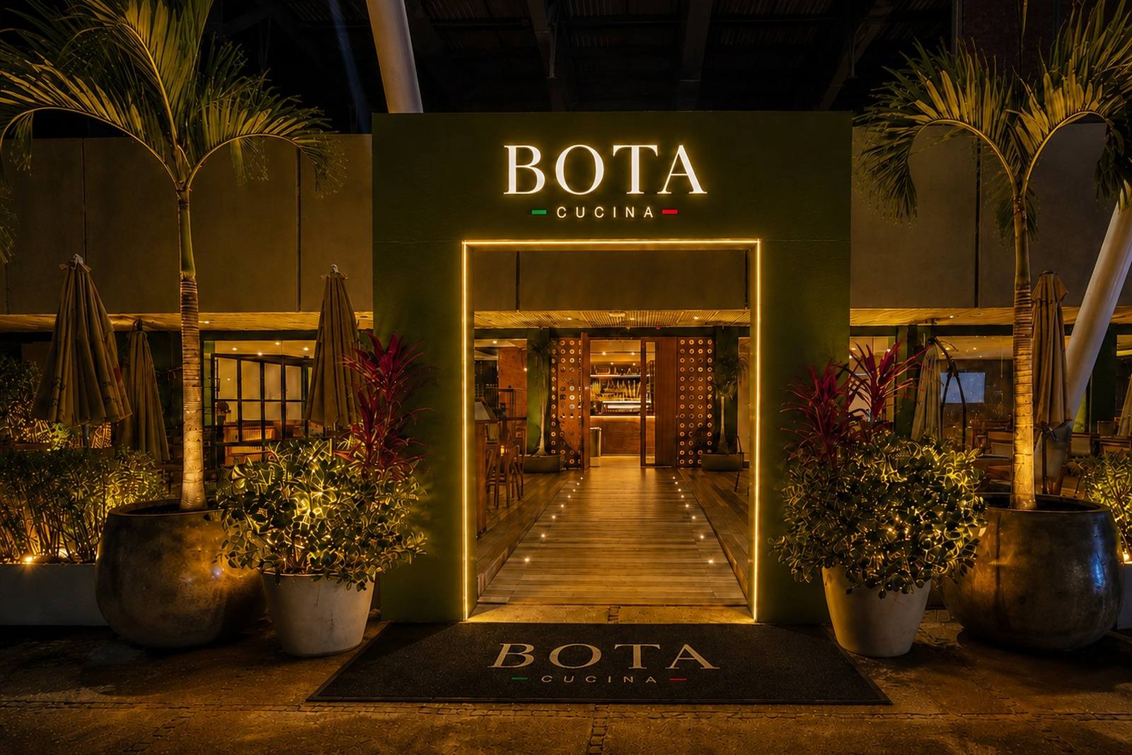 Illuminated BOTA Cucina entrance at night, with the BOTA CUCINA sign