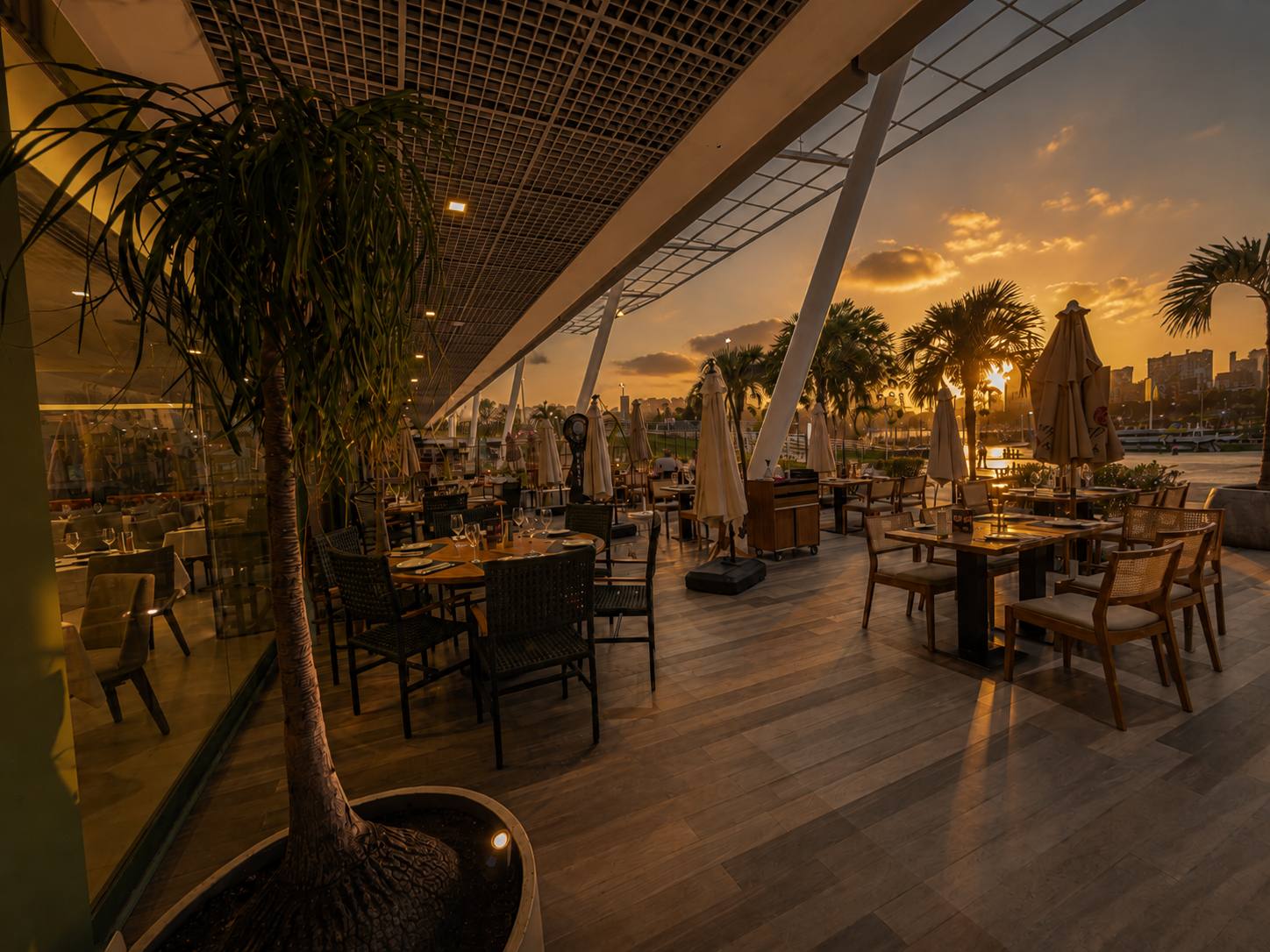 Varanda do BOTA ao pôr do sol, com as mesas postas de frente para a marina